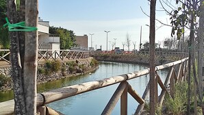 Un puente de madera sobre un río tranquilo, con un muro de piedra y una valla a un lado.