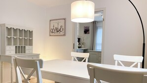 A dining area with a white table and chairs, a pendant light, a white cabinet with shelves, and a framed picture on the wall. - Minihotel (Pforzheim)