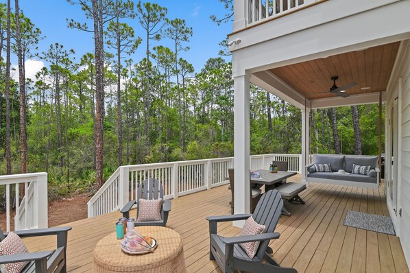 A covered deck with outdoor seating, a table, and a hanging chair.