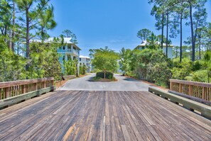 A wooden boardwalk leading to a row of two-story houses surrounded by trees.