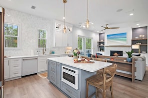 A modern kitchen with a large island, white cabinetry, and a built-in oven. - Luxury 30A Gem | 4 Bikes | Huge Deck | Fire Pit (Rosemary Beach)