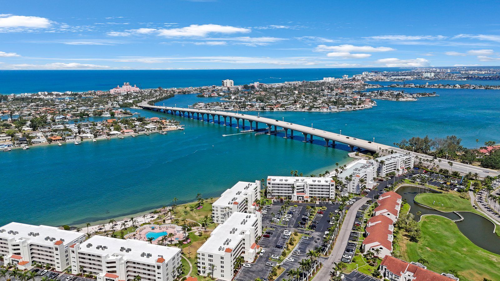 Un paysage urbain côtier avec un pont imposant, des propriétés situées en bord de mer et un terrain de golf.