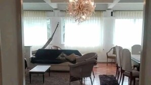 Amplia sala de estar con una lámpara moderna, un sofá, una mesa de centro y un comedor con sillas.