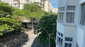 Vista de una calle con un edificio a la derecha, una avenida arbolada y un camión estacionado.