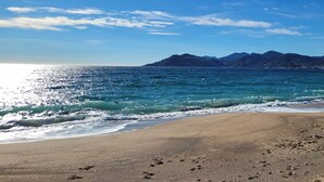 A beach with clear water, a sandy shore, and mountains in the background. - "Theo'z Roof Top & Sea View" (Cannes)