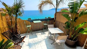 A patio with a table and chairs, a bamboo fence, and a view of the sea. - "Theo'z Roof Top & Sea View" (Cannes)