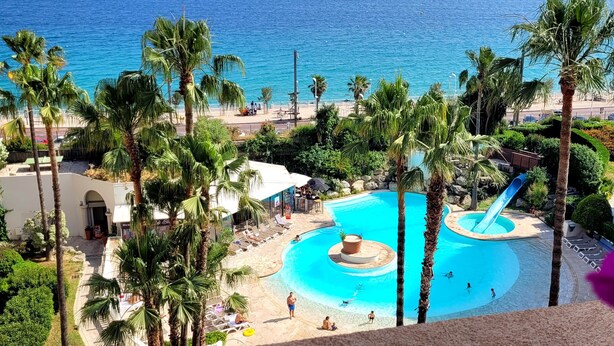 A resort with a pool, palm trees, and a view of the sea. - "Theo'z Roof Top & Sea View" (Cannes)