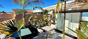 A patio area with a table and chairs, surrounded by plants and a glass door leading to a balcony. - "Theo'z Roof Top & Sea View" (Cannes)