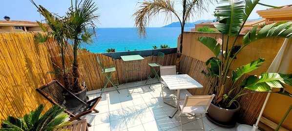 A patio with a table and chairs, a bamboo fence, and a view of the sea. - "Theo'z Roof Top & Sea View" (Cannes)