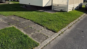 Una casa móvil de una sola planta con un pequeño porche y un patio cercado.