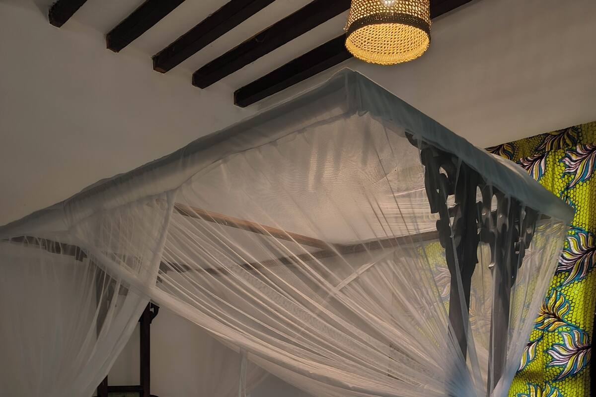 A bed with a canopy, a patterned pillow, and a decorative headboard.