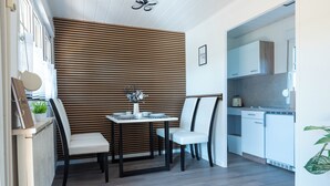 Een eethoek met een tafel en stoelen, een wand met houten latten en een keuken op de achtergrond.