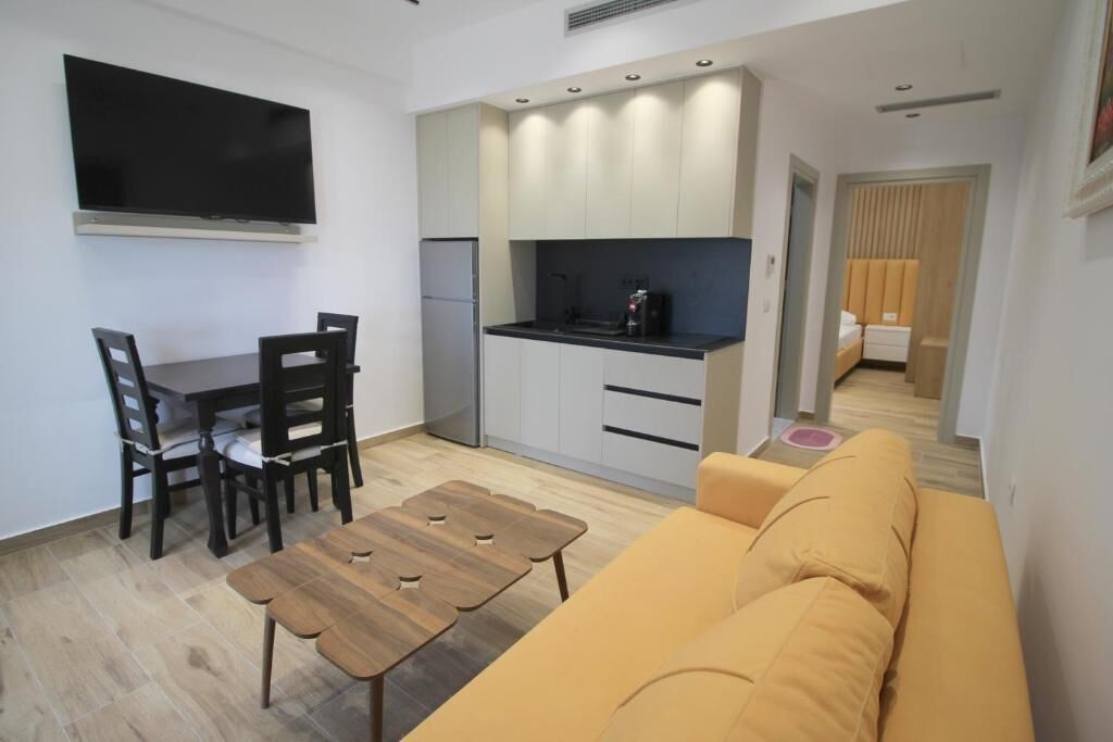 A compact living space with a kitchenette, a dining area with a table and chairs, and a sofa.