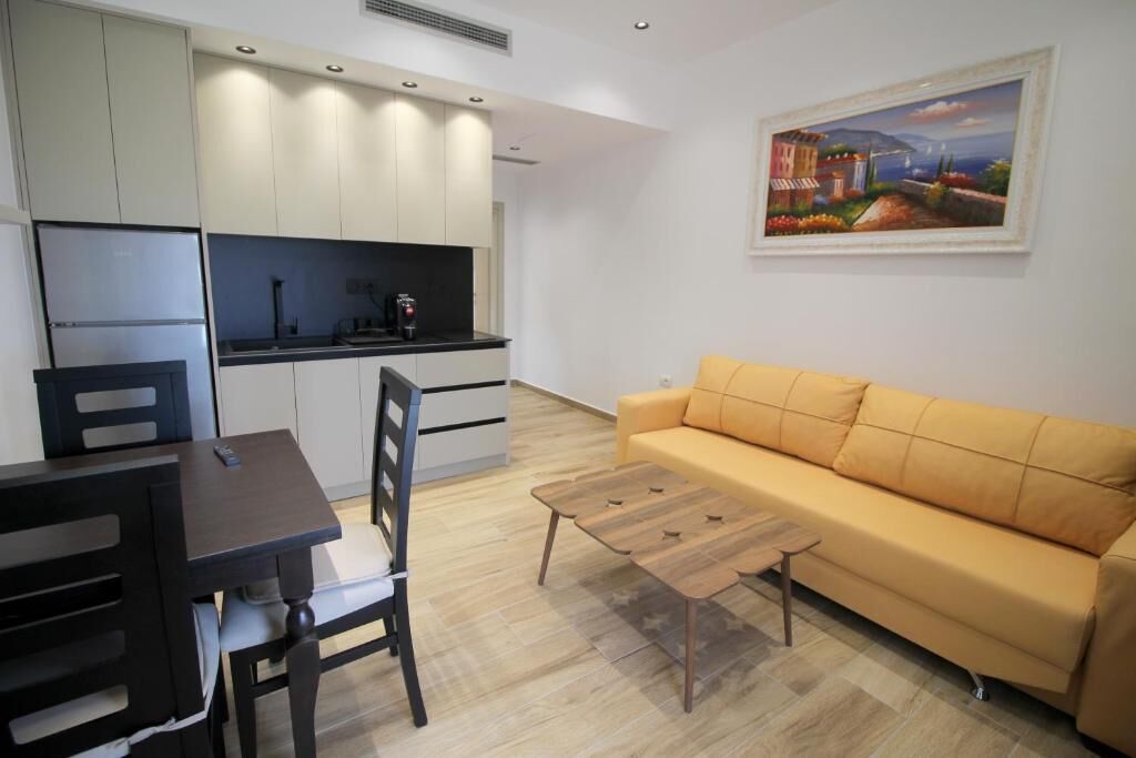 A compact living space with a kitchenette, a sofa, and a painting on the wall.