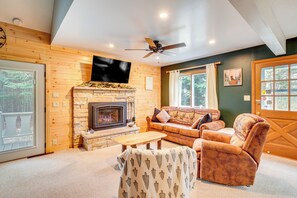 A cozy living room with a fireplace, a sofa, a chair, and a television mounted on the wall. - Boat, Paddle, UTV & More: Getaway in Saint Germain (St Germain)
