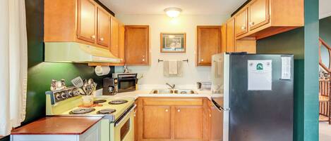 A kitchen with wooden cabinets, a stove, a refrigerator, and a sink.