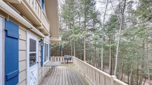 A wooden deck with a table and chairs, surrounded by a white railing, overlooking a forested area. - Boat, Paddle, UTV & More: Getaway in Saint Germain (St Germain)