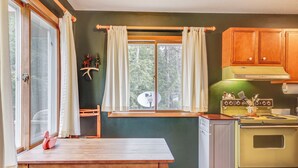 A kitchen with a green stove, wooden cabinets, and a window with curtains. - Boat, Paddle, UTV & More: Getaway in Saint Germain (St Germain)