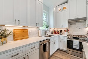 Eine moderne Küche mit weißen Schränken, einem Edelstahl-Geschirrspüler, einem Backofen und einer Holztischplatte.