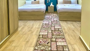 A modern hotel room with two beds, a blue accent wall, and a patterned rug. - red pyramids hotel (Giza Governorate)
