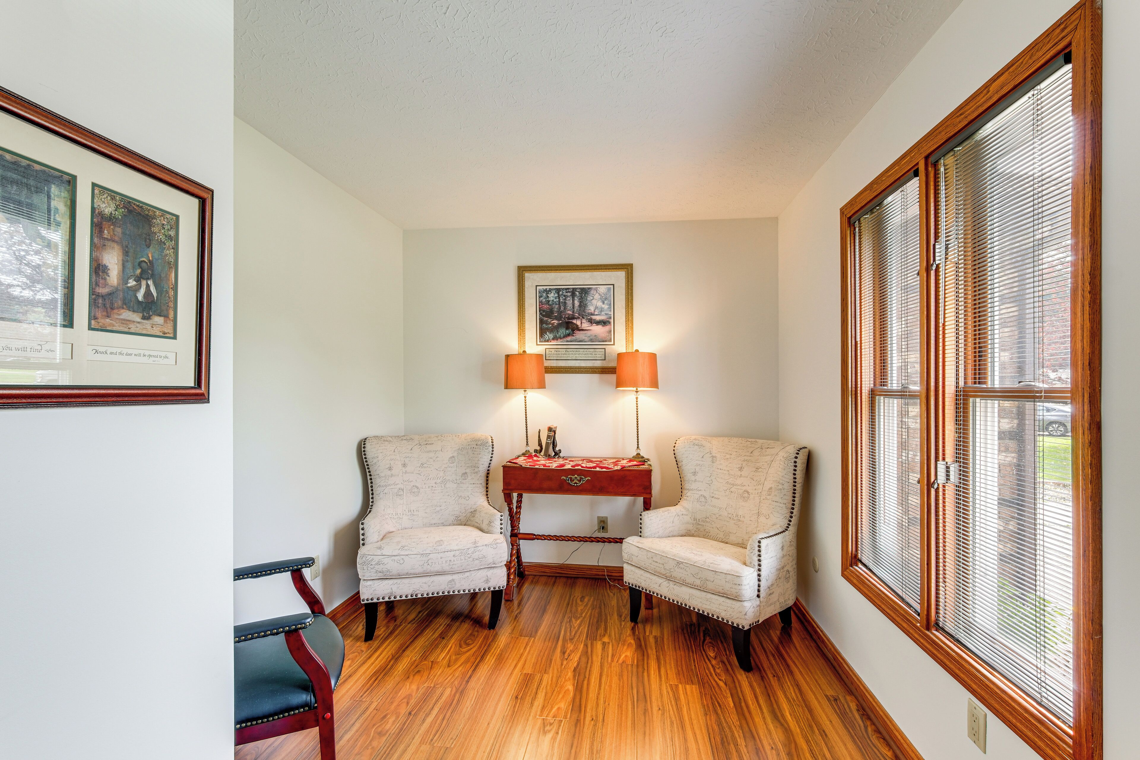 A room with two armchairs, a small table, and a framed picture on the wall.