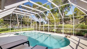 A covered outdoor swimming pool with lounge chairs and a pergola structure.