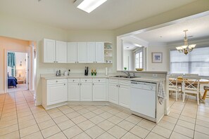 A modern kitchen with white cabinetry, a dishwasher, and a dining area with a table and chairs. - 4 Golf Courses On-site: North Myrtle Beach Villa! (North Myrtle Beach)