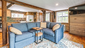 A cozy living area with a blue sectional sofa, a small wooden coffee table, and a patterned rug. - Hocking Hills 'social Distance Cabin' w/ Hot Tub (Laurelville)
