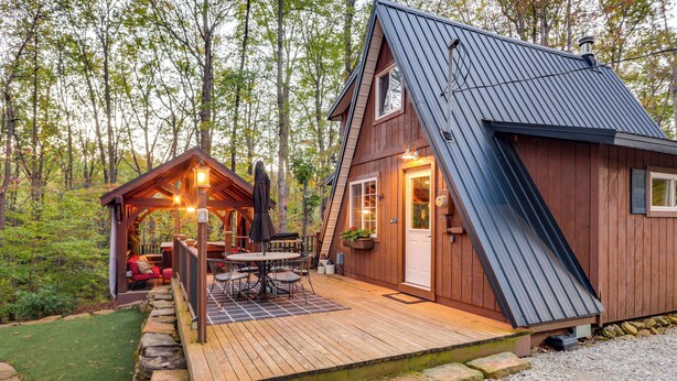 A wooden cabin with a deck, a small porch, and a dining area with outdoor furniture. - Hocking Hills 'social Distance Cabin' w/ Hot Tub (Laurelville)