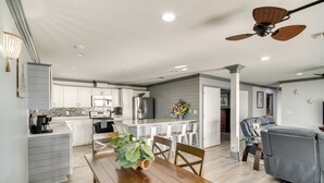 A modern kitchen with white cabinets, a central island, and a dining area with a wooden table and chairs. - Front Row Beachfront Long Beach Getaway (Long Beach)