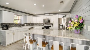 A modern kitchen with white cabinetry, granite countertops, and stainless steel appliances. - Front Row Beachfront Long Beach Getaway (Long Beach)
