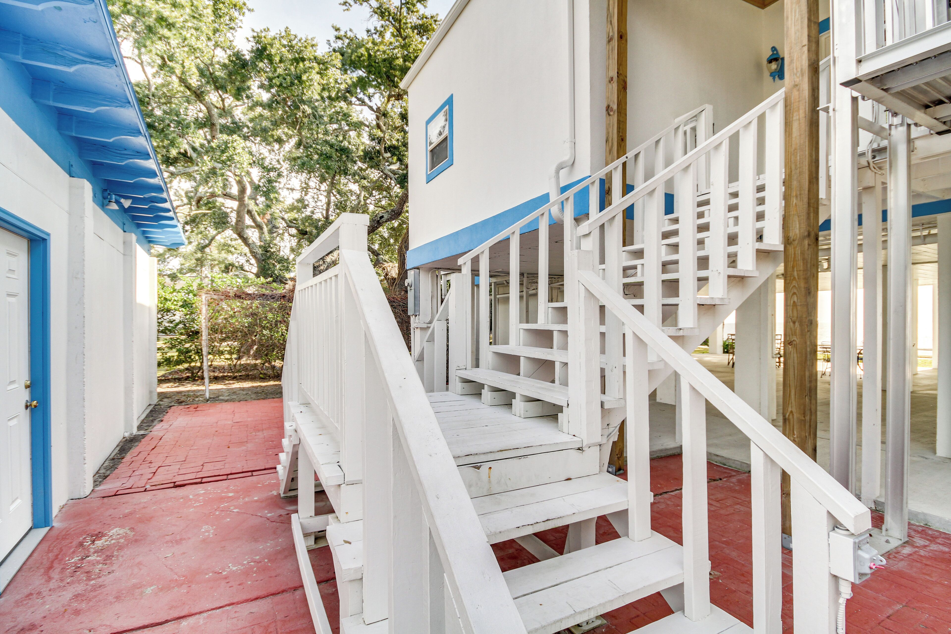 A white staircase with a red floor leading to a building entrance.