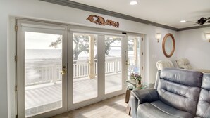 A room with a view of the ocean through large sliding glass doors, a leather sofa, a small table with a vase, and a wall-mounted mirror. - Front Row Beachfront Long Beach Getaway (Long Beach)