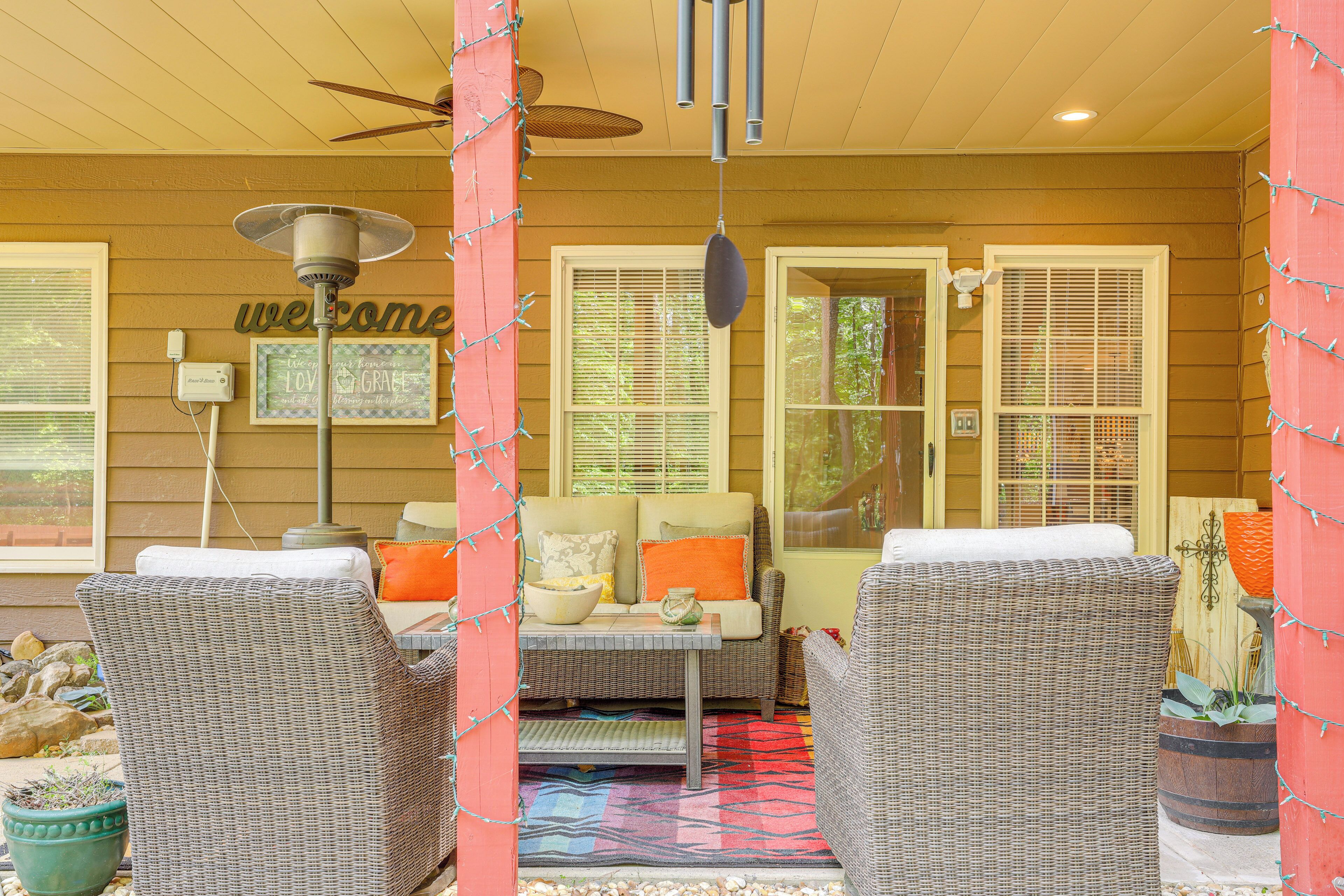 A covered outdoor seating area with wicker furniture, a ceiling fan, and a 'welcome' sign.