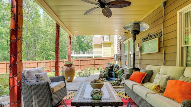 A covered patio with wicker furniture, a table with a bowl, and a 'welcome' sign. - Spacious Yard & Bbq: Chic Escape in Lawrenceville! (Lawrenceville)