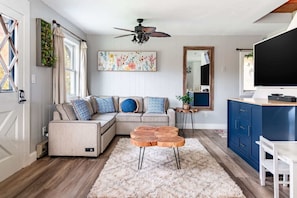 Relax in this inviting living space with a beige sofa, wooden coffee table, and large mirror.