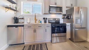 A modern kitchen with stainless steel appliances, white cabinetry, and a window with blinds. - ‼️Morrison Getaway‼️ - 2BR House,  BBQ , Free Parking (Morrison)