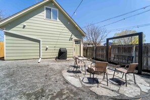 A house with a patio area featuring outdoor furniture and a swing set.