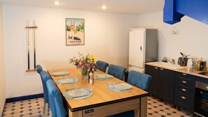 A dining area with a wooden table set for six, blue upholstered chairs, a vase with flowers, and a painting on the wall. - Country apartment (Moulins)