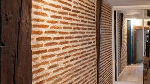 Een gang met een bakstenen muur en houten vloer.