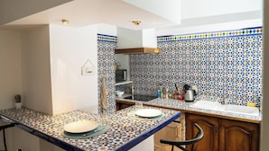 Cozinha com painel de azulejos, pia e bancada com prato e copo.