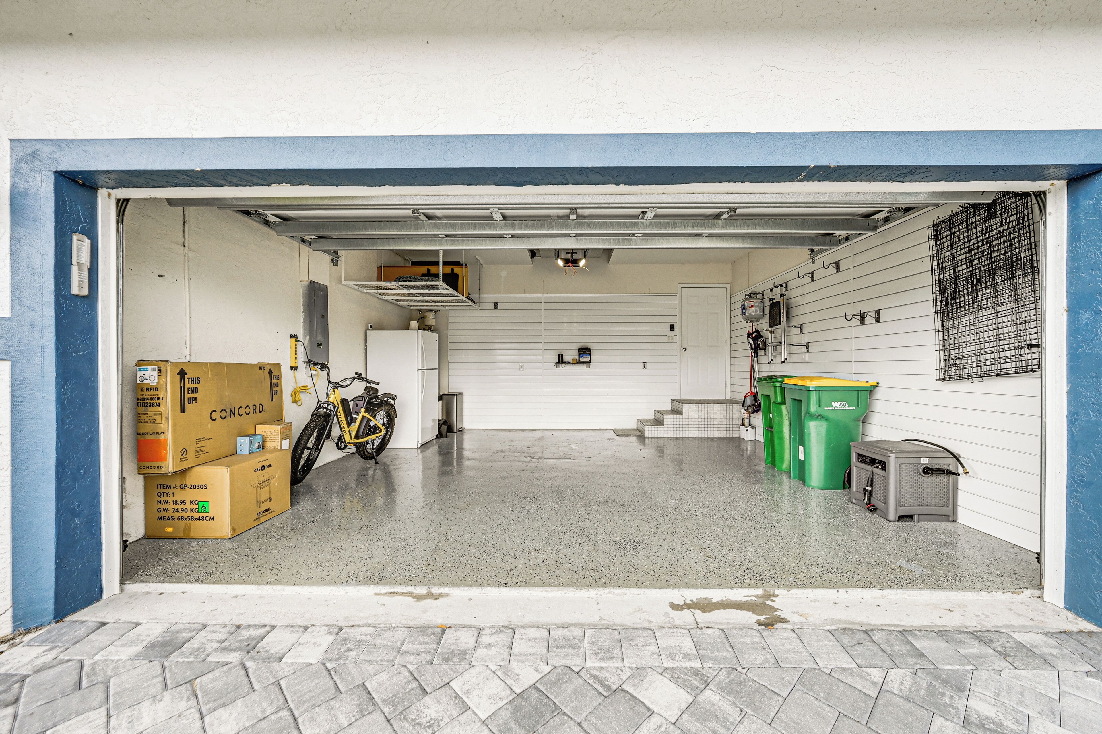 Uma garagem com chão de concreto, uma bicicleta e várias caixas de papelão.