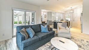 A modern living room with a grey sofa, a white coffee table, and a ceiling fan.