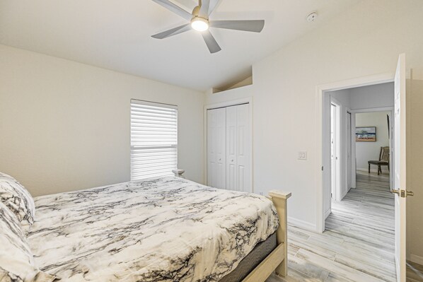 A bedroom with a bed, a ceiling fan, a door, and a hallway leading to another room. - < 1 Mi to Tigertail Beach: Waterfront Gem w/ Dock! (Marco Island)