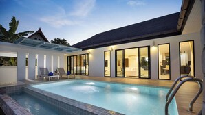 A modern pool area with clear glass walls, lounge chairs, and a well-lit interior. - Designer 3BR Villa Silver Pool in Kamala (Kamala)
