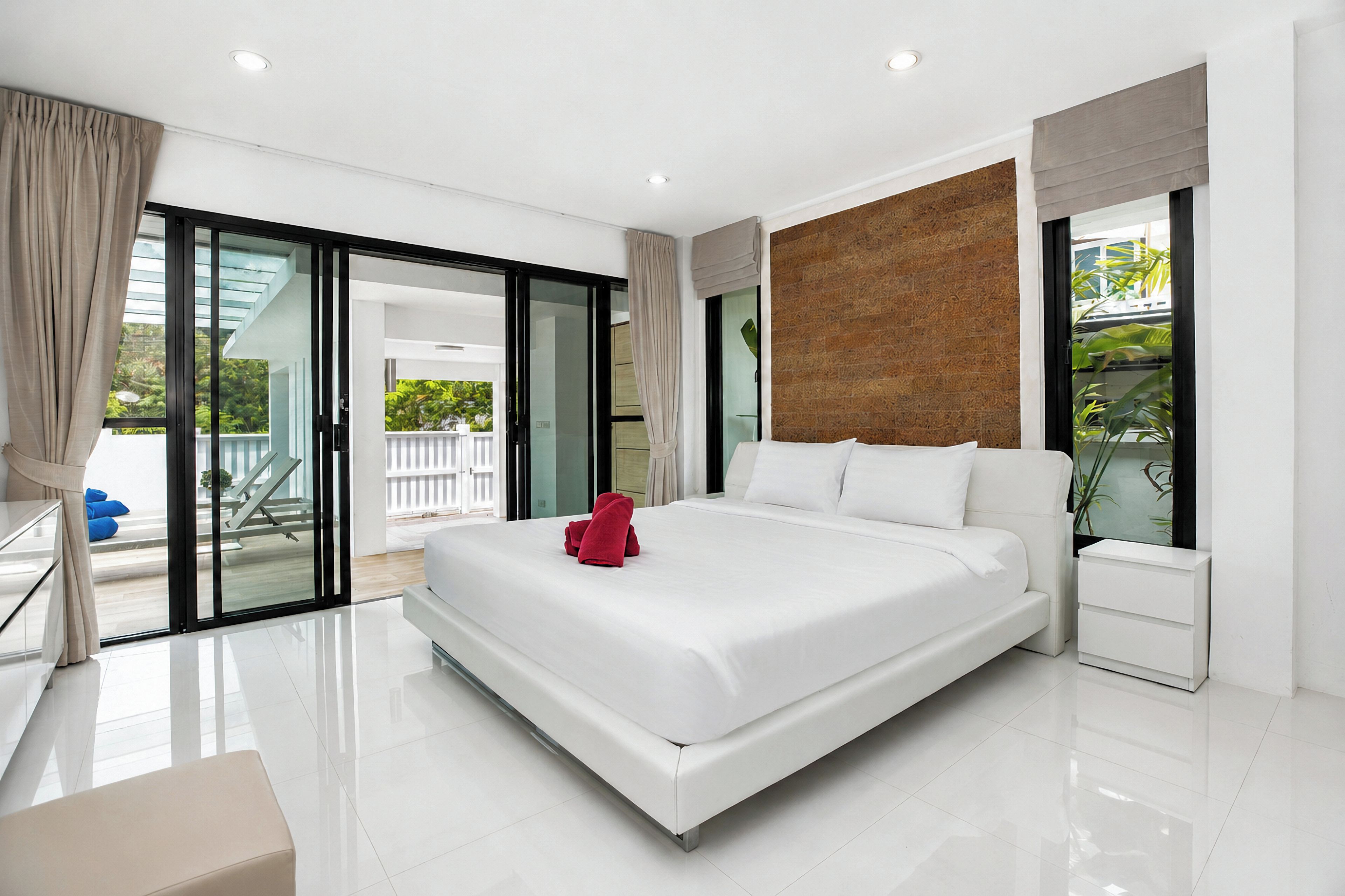 A modern hotel room with a large bed, a glass door leading to a balcony, and a wooden accent wall.