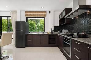 A modern kitchen with dark cabinetry, a stainless steel refrigerator, a microwave, and a stove.