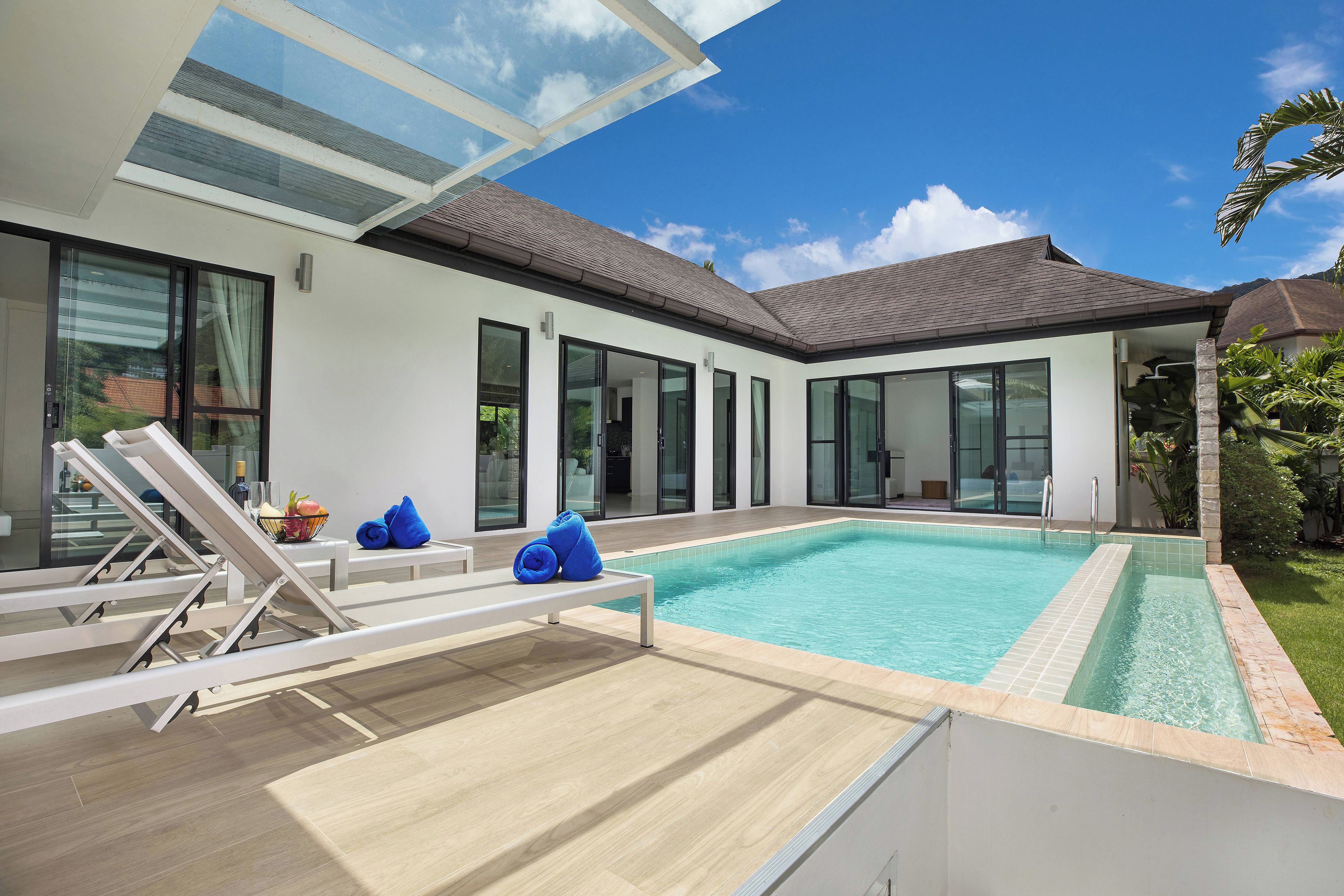 A modern house with a swimming pool, large windows, and a glass ceiling.