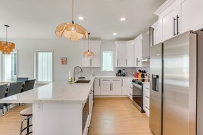 A modern kitchen with white cabinets, a large island, stainless steel appliances, and pendant lighting. - Swim Spa, Game Room: New Build Navarre Beach House (Navarre)