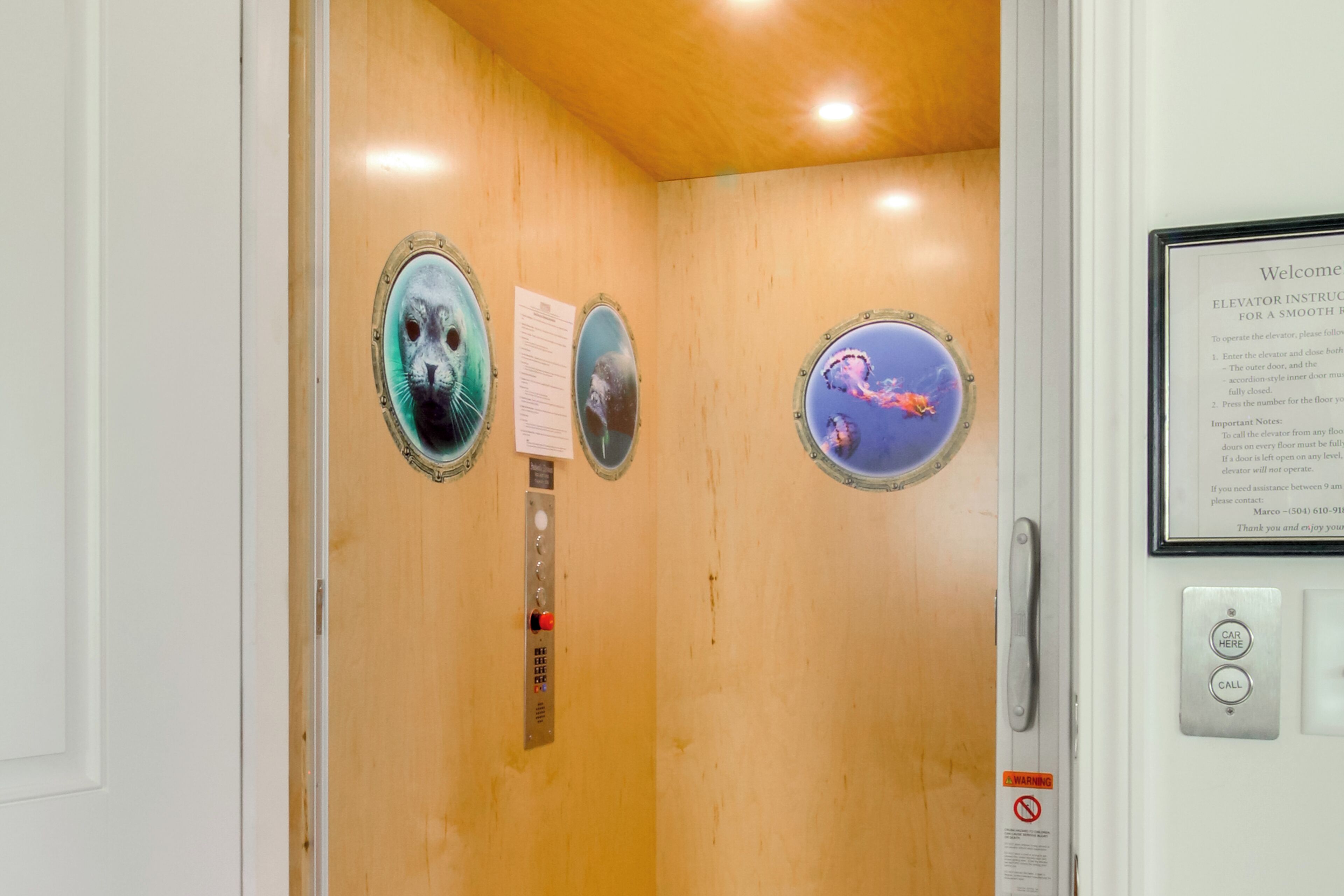 An elevator interior with a wooden finish, a control panel, and three circular decorative panels with images.